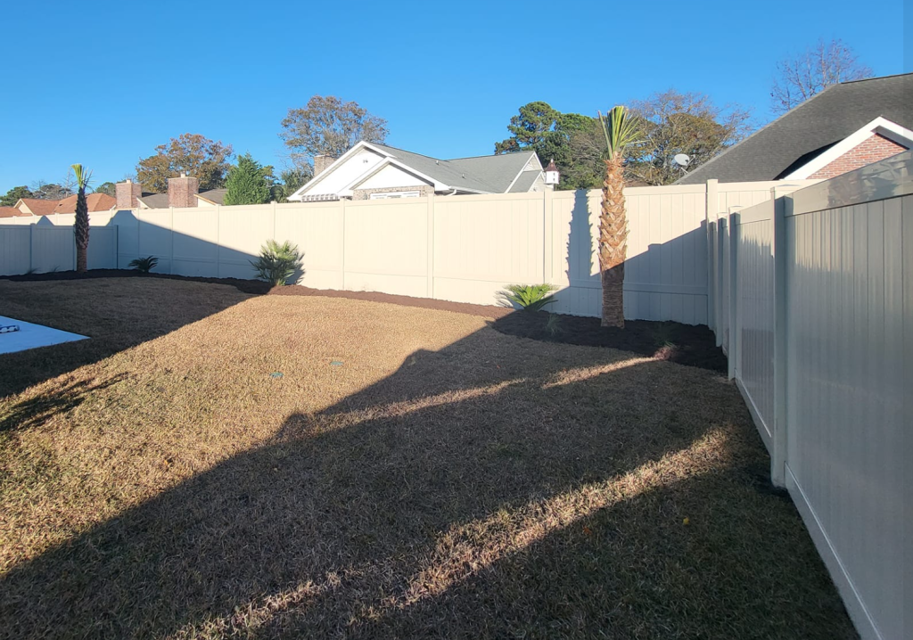 white Vinyl fence surrounding a yard with a new palm tree in the background
