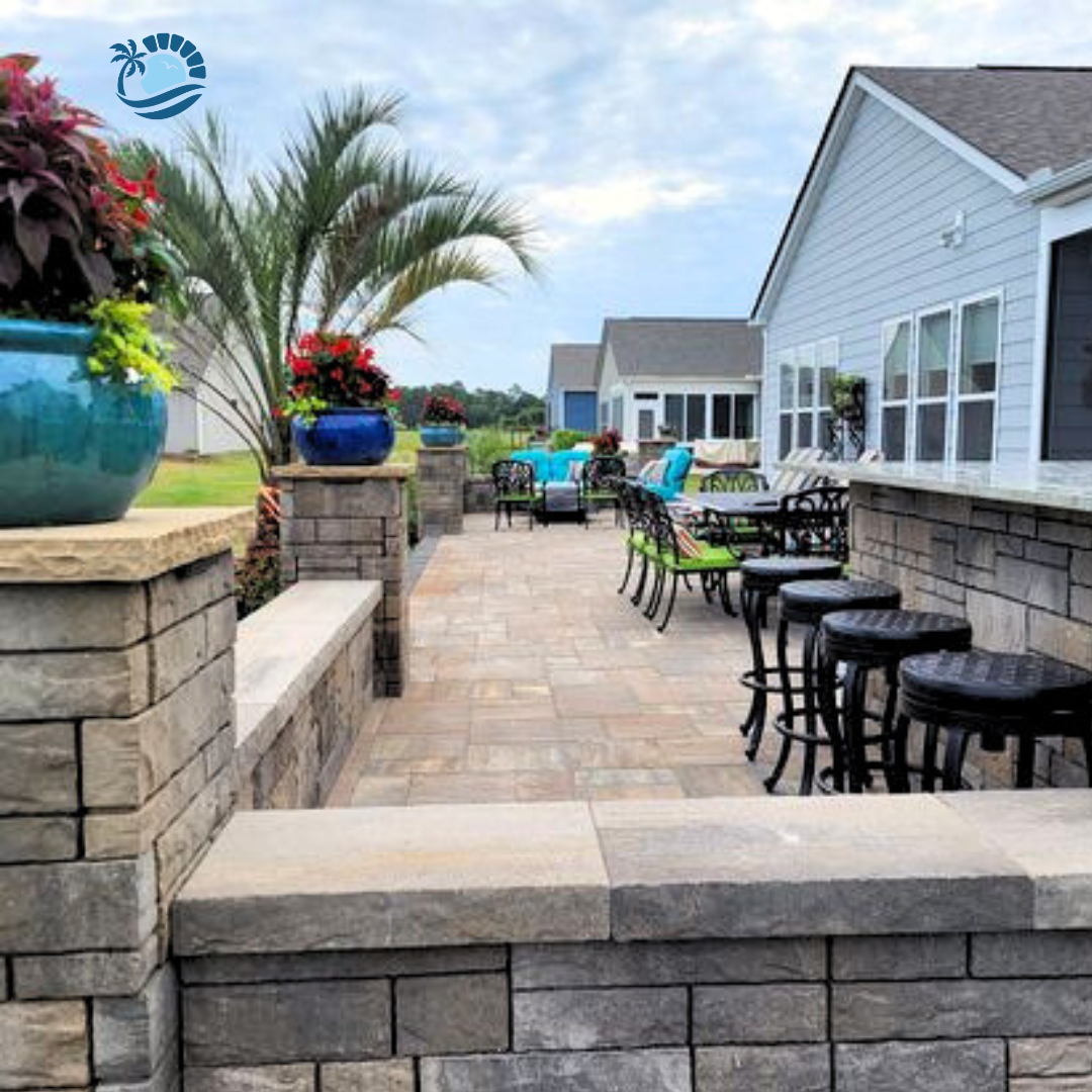 hardscape wall built with tan pavers surrounding patio with bar stools to the left