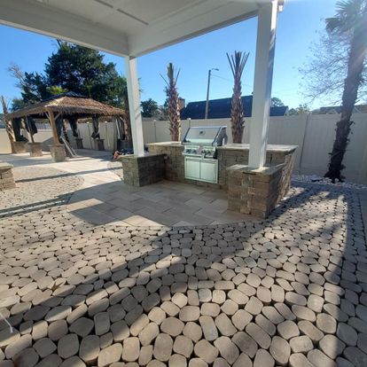 brown circle paver patio design with a pergola and outdoor kitchen
