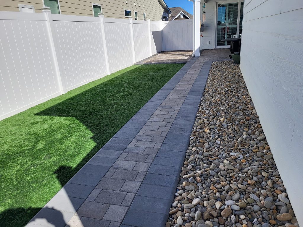 landscape rocks with a paver walkway and artificial turf