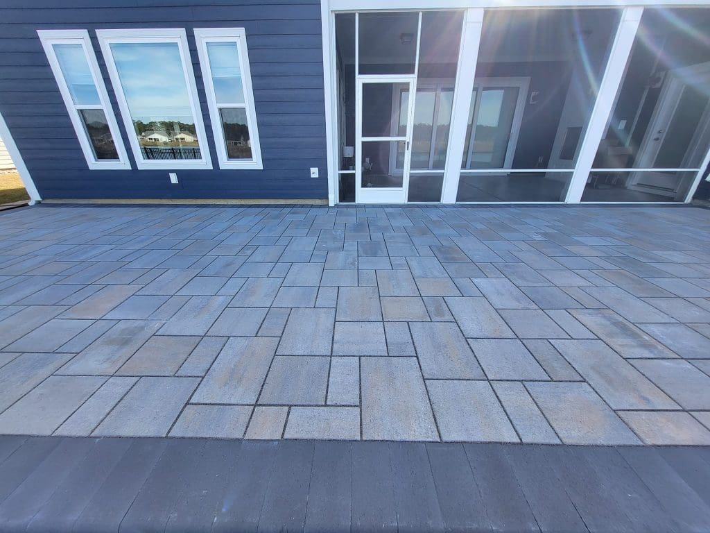 gray sleek porcelain pavers for a patio with a blue house in the background