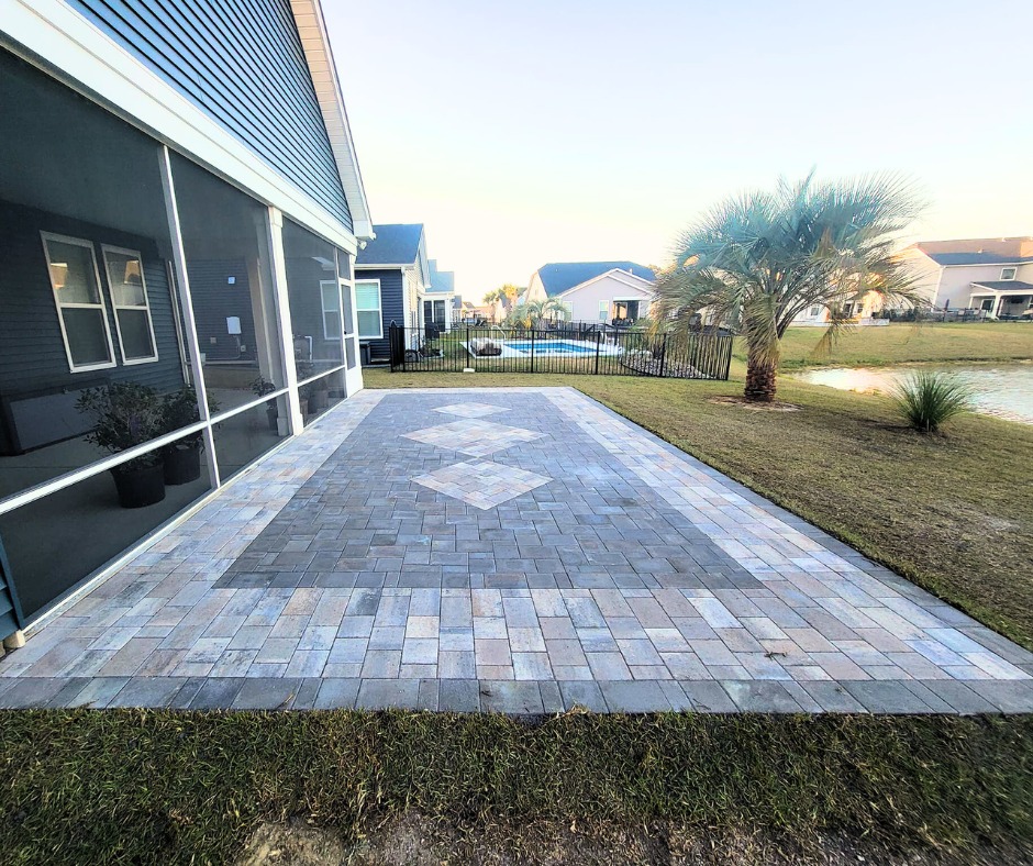 Belgard paver patio with a diamond design with palm trees to the left of the backyard