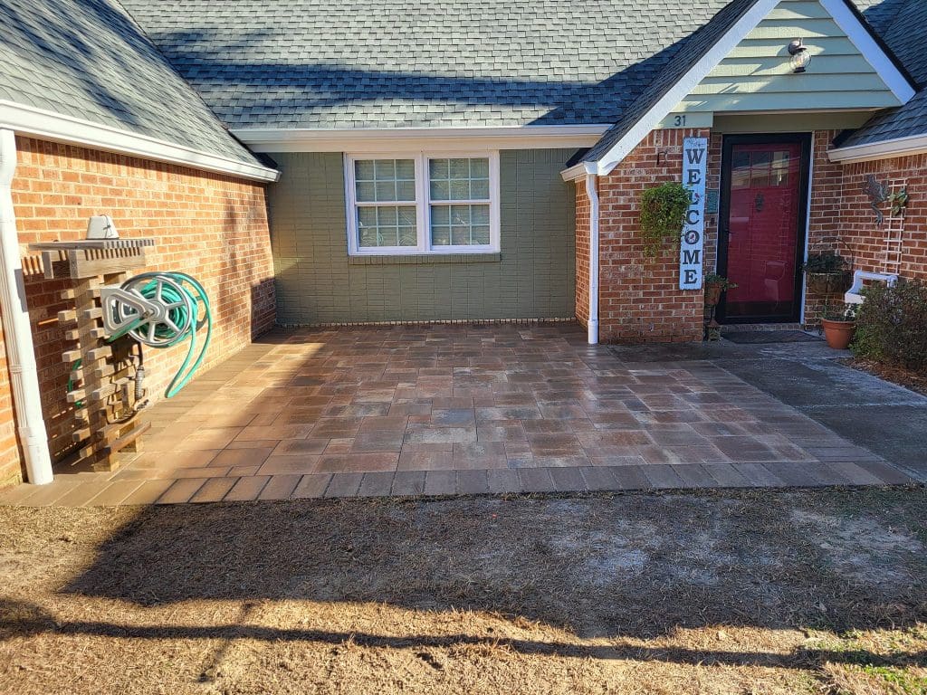brick paver patio in front of a brick home with sod laid in front of the patio
