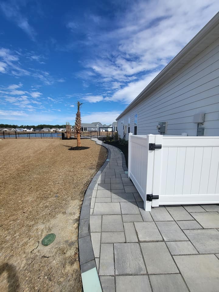 paver walkway with a fence enclosure for garbage on the left side