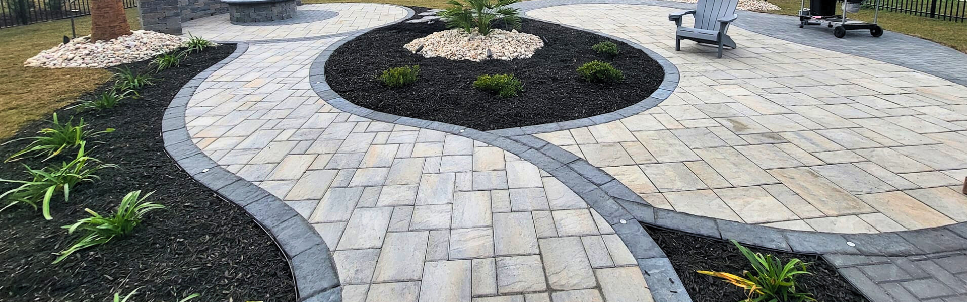 gray and tan paver patio and walkway with a palm tree in the middle