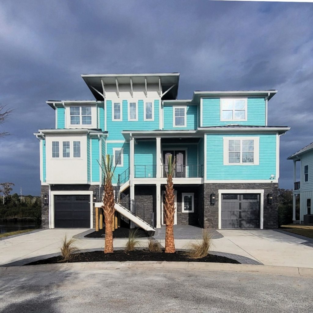 Circle concrete driveway with gray Belgard pavers along the sides—black mulch laid to the right of the driveway with palm trees.