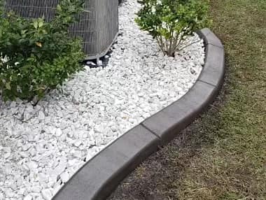 white rocks with plants and a concrete border