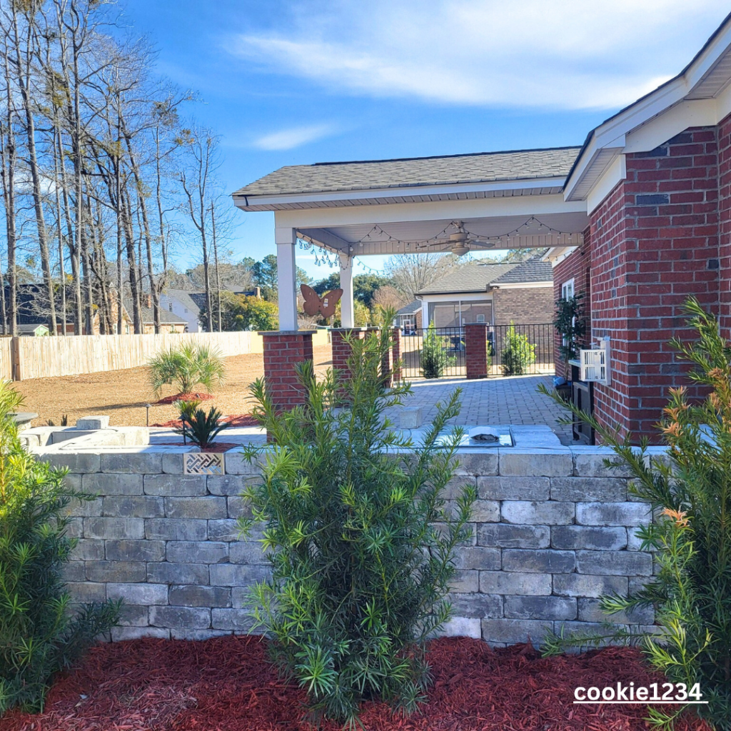paver retaining wall with plants and red mulch by Elite coastal Landscaping