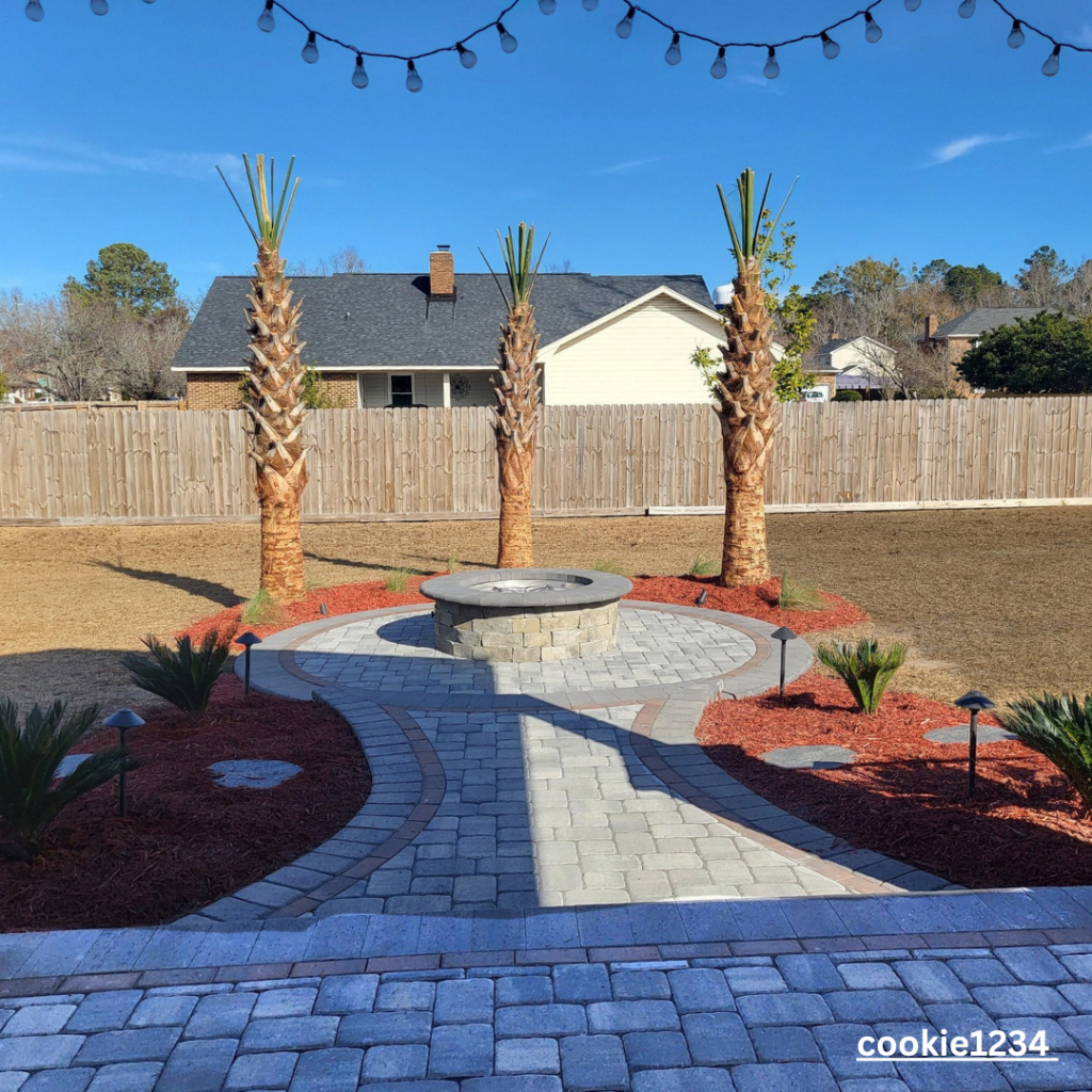 3 palm trees with red mulch and a paver outdoor fire pit